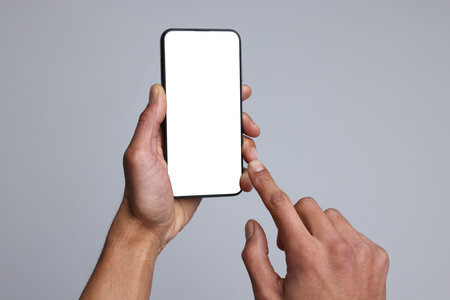 Man holding smartphone with blank screen on light gray background, closeup. Mockup for design