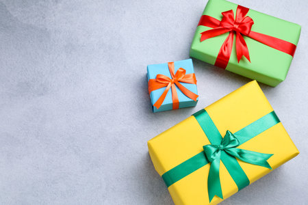 Beautiful wrapped gifts on gray table, flat lay. Space for text