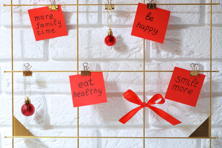 New Year aims. Paper notes with resolutions and festive decor near white brick wall