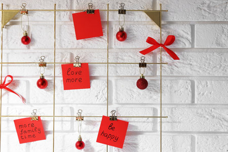 New Year aims. Paper notes with resolutions and festive decor near white brick wall