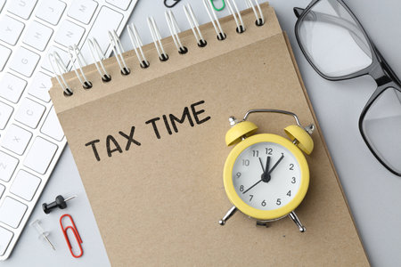 Tax time. Alarm clock, notebook, glasses and computer keyboard on table, top viewの写真素材