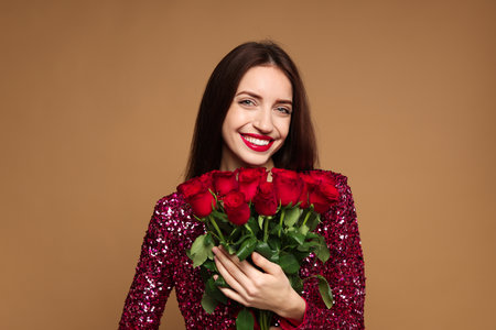 St. Valentine's Day. Beautiful woman with bouquet of roses on beige backgroundの写真素材