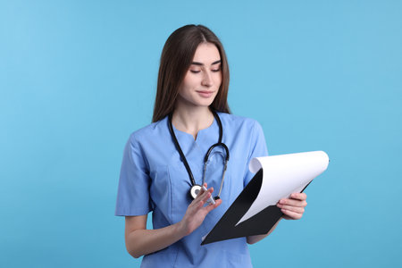 Portrait of medical assistant with clipboard on light blue background