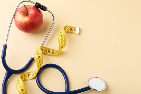 Ripe apple, measuring tape and stethoscope on beige background, flat lay. Space for textの写真素材