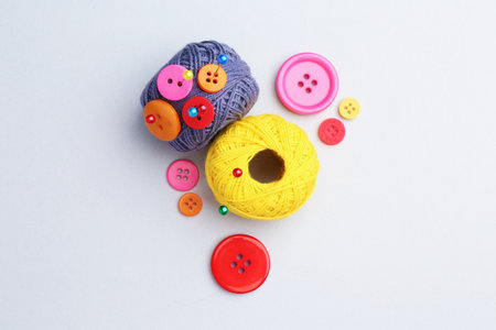 Balls of yarns with pins and buttons on white background, flat layの写真素材