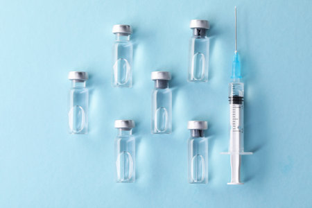 Vaccine in vials and syringe on light blue background, flat layの写真素材