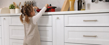 Child safety at home, Little girl reaching for pot on stove in kitchenの写真素材
