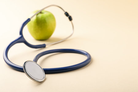 Ripe apple and stethoscope on beige background, selective focus. Space for textの写真素材