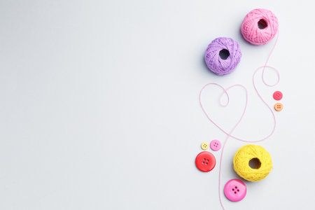 Balls of yarns and buttons on white background, flat lay. Space for textの写真素材