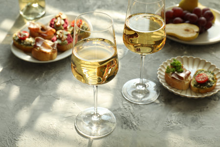 White wine in glasses, bruschette and snacks on gray tableの写真素材