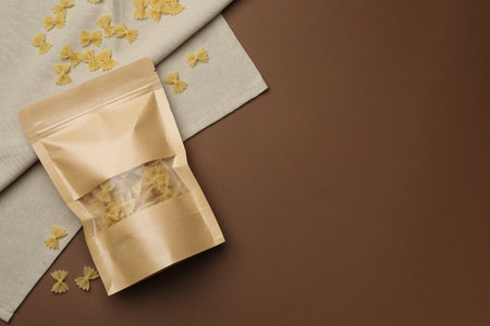 Stand-up pouch with pasta on brown background, flat lay. Space for textの写真素材