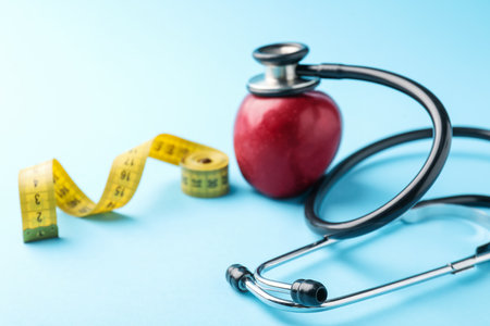 Ripe apple, measuring tape and stethoscope on light blue background, closeupの写真素材