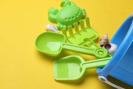 Children's beach toys and seashells on yellow background, closeup. Space for textの写真素材