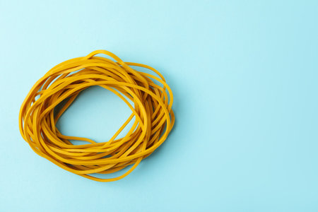 Many yellow rubber bands on light blue background, top view. Space for textの写真素材