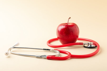Ripe apple and stethoscope on beige background, closeup. Space for textの写真素材