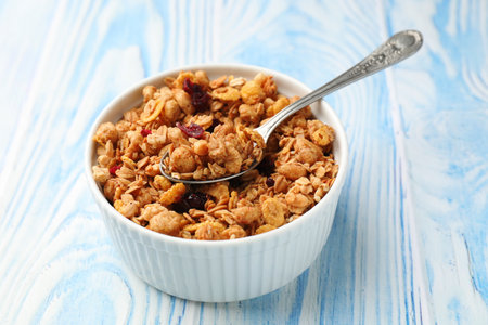 Tasty granola with dried fruits in light blue wooden table, closeup