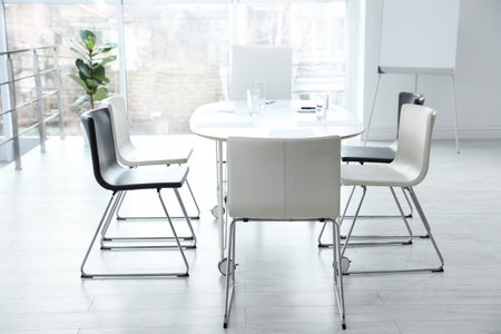Stylish chairs, table and houseplant in office. Interior design