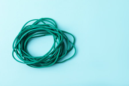 Many green rubber bands on light blue background, top view. Space for textの写真素材