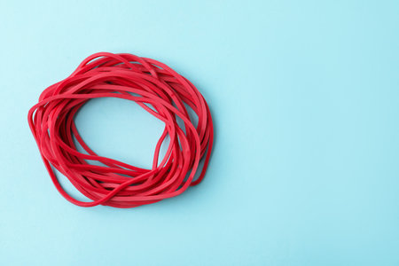 Many red rubber bands on light blue background, top view. Space for textの写真素材