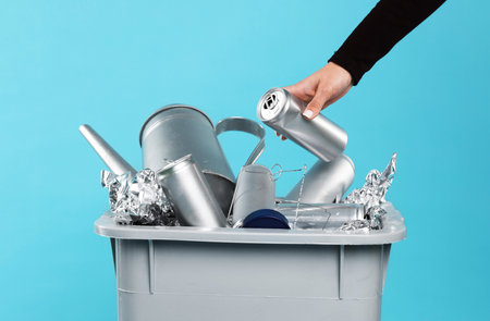 Woman garbage throwing into trash bin on light blue background, closeup. Waste sortingの写真素材