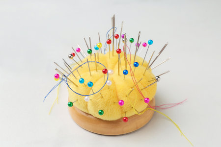 Pincushion with needles and pins on white marble table, closeupの写真素材