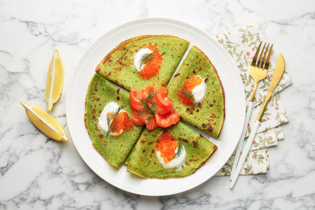 Tasty spinach crepes with salmon, sour cream, lemon and dill on white marble table, flat layの写真素材