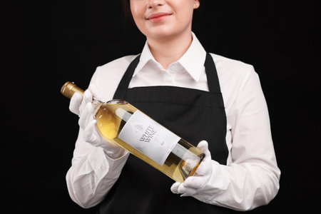 Professional sommelier with bottle of white wine on black background, closeupの写真素材