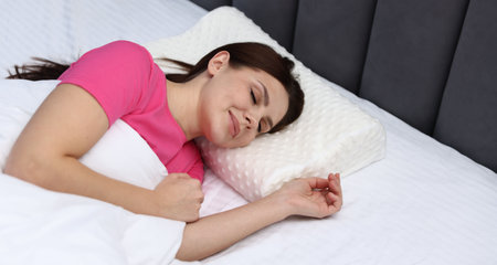 Young woman sleeping on bed with orthopedic pillow. Healthy postureの写真素材