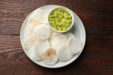Tasty rice paper chips and wasabi on wooden table, top view