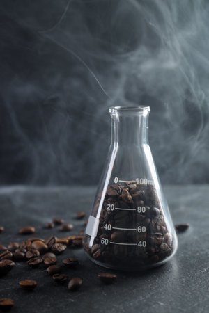 Glass flask with coffee beans on black table, closeupの写真素材