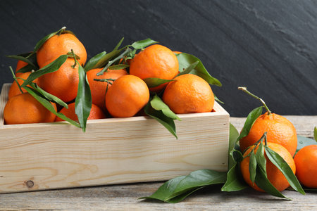 Fresh ripe tangerines with leaves on wooden table, closeupの写真素材