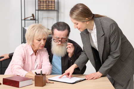 Notary consulting senior couple about Last Will and Testament at wooden desk in office