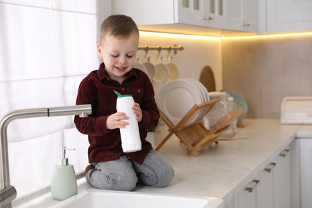 Child safety at home. Little boy playing near sink in kitchen, space for textの写真素材