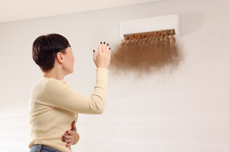 Woman unhappy because of bad smell from air conditioner indoors. Dirty air flows from appliance