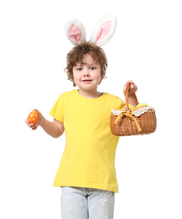 Easter celebration. Happy little boy in headband with bunny ears holding wicker basket full of...