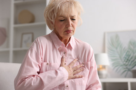 Heart attack. Senior woman suffering from pain in chest indoors