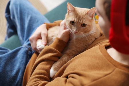 Man with his cute cat on sofa at home, closeup