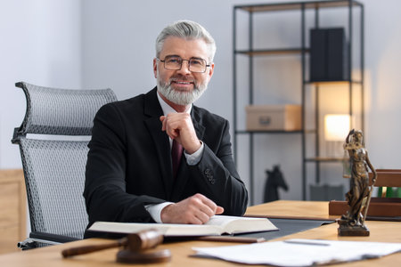 Portrait of smiling notary in glasses and suit with book at table in office