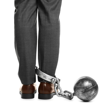 Businessman with metal ball and chain on his leg against white background, closeupの写真素材