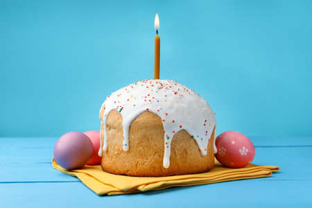 Beautiful Easter cake with candle and eggs on blue wooden table