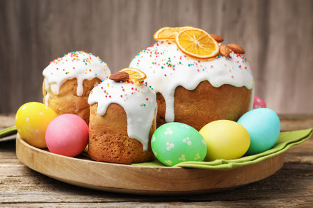 Delicious decorated Easter cakes and eggs on wooden table, closeup