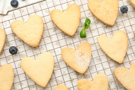 Tasty heart shaped butter cookies, mint and blueberries on table, flat lay