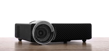 Modern video projector on wooden table against white background