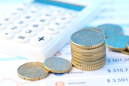 Many coins and calculator on document, closeup