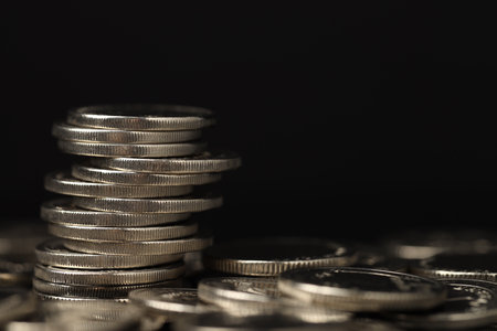 Stack of coins on black background, closeup. Space for text