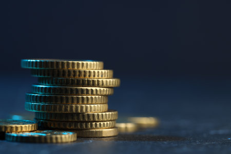 Many stacked coins on table against blurred background, closeup. Space for text