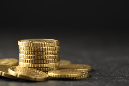 Many stacked coins on table against blurred background, closeup. Space for text