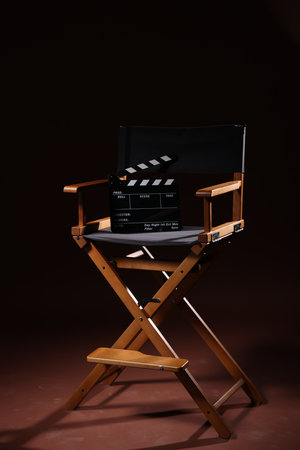 Film director's chair with clapperboard on dark brown backgroundの写真素材