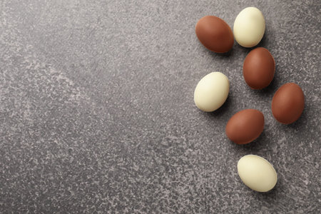 Easter celebration. Many chocolate eggs on gray textured table, flat lay with space for textの写真素材