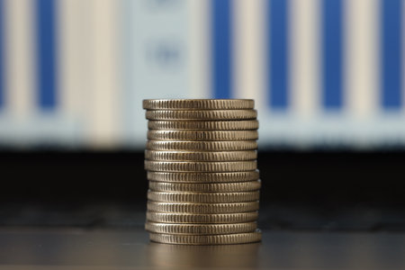 Stack of coins on laptop against blurred background, closeup